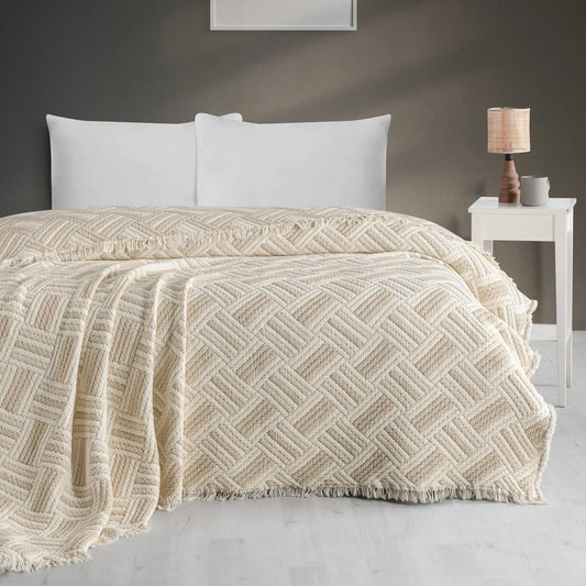 Jakarlı desenli müslin bej yorgan, dört kenarı saçaklı, yatak örtüsü olarak kullanılıyor.