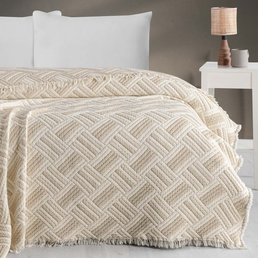 Jakarlı desenli müslin bej yorgan, dört kenarı saçaklı, yatak örtüsü olarak kullanılıyor.