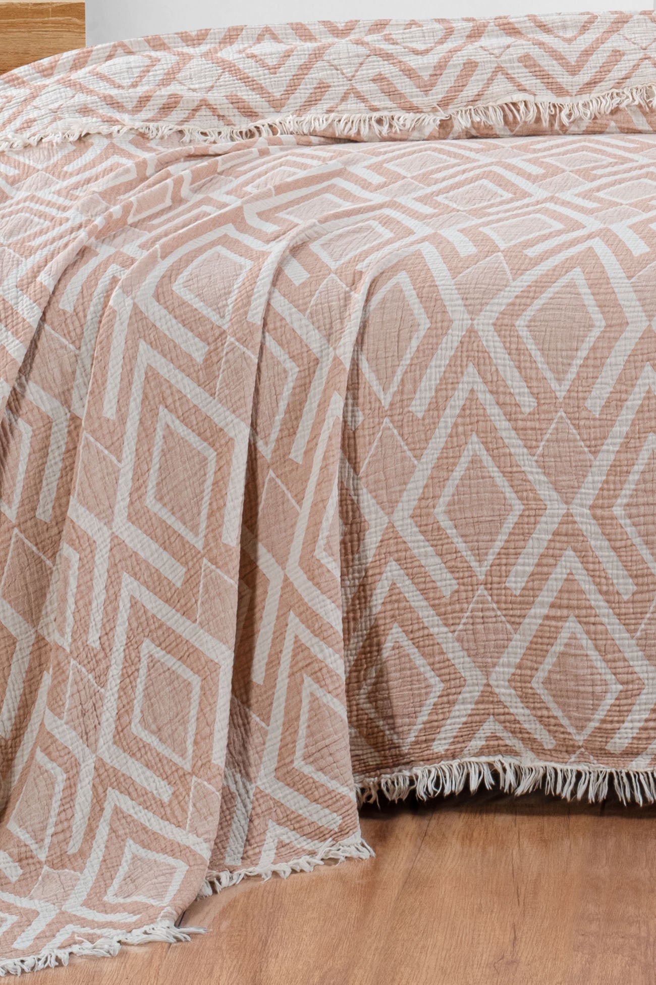 Crea 3-layer jacquard muslin blanket in terracotta, 100% cotton, draped elegantly on a bed.